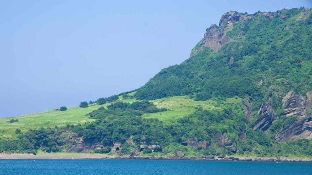 Grassy pastures climb Seongsan Ilchulbong’s lower slopes toward sheer cliffs.