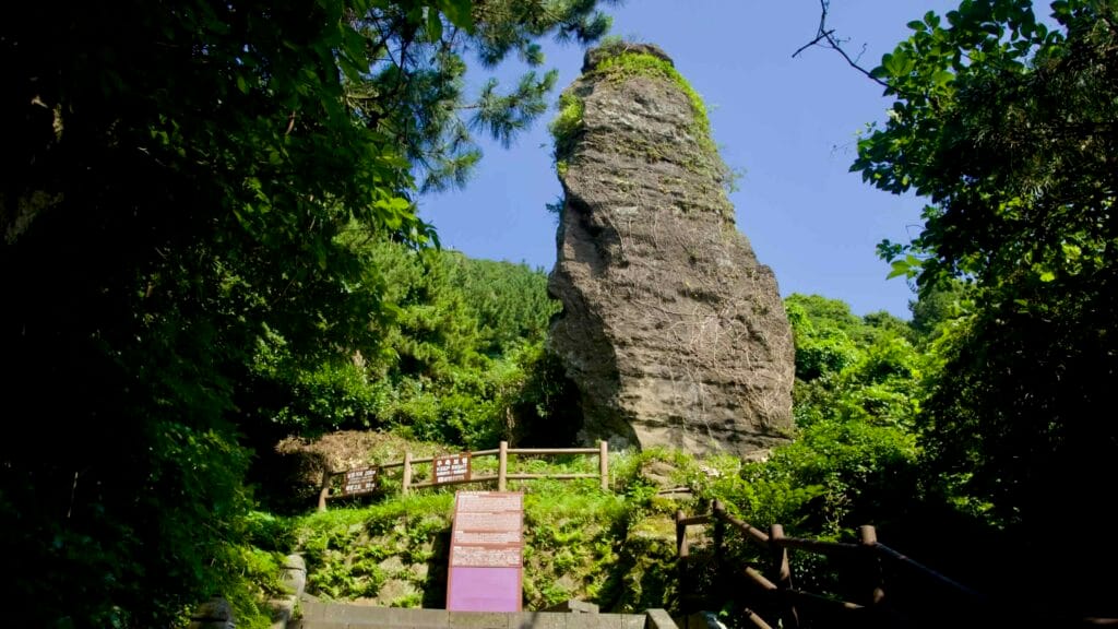 A vertical rock pinnacle rises beside the Seongsan Ilchulbong hiking path.