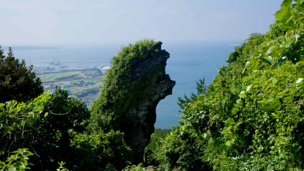 A beak-shaped lava outcrop juts into the blue sea from the cliffs of Seongsan Ilchulbong.