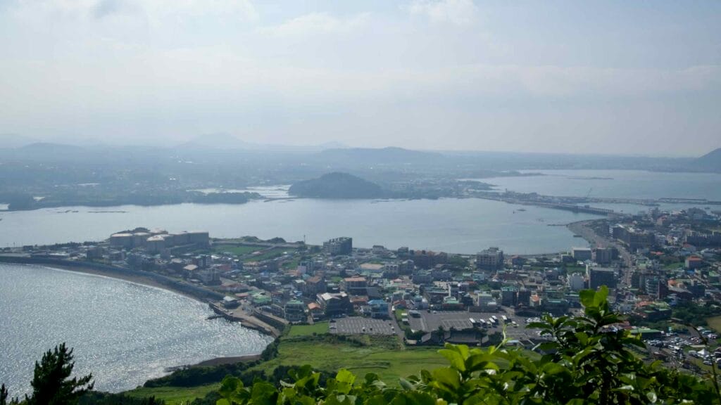 A hazy panoramic view stretches across the bay toward Seongsan-ri and the open sea.