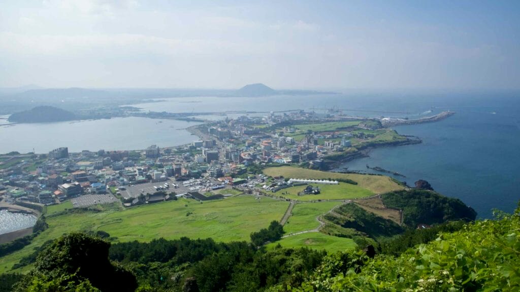 A broad panorama overlooks Seongsan-ri and its harbor from the slopes of Seongsan Ilchulbong.