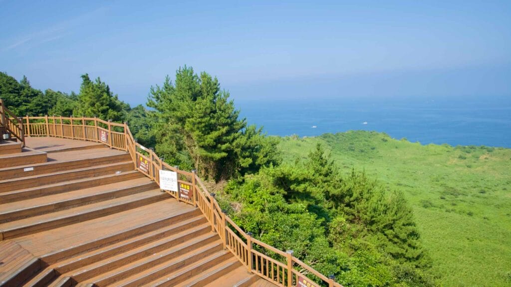 A tiered viewing deck overlooks the green crater of Seongsan Ilchulbong and the sea beyond.