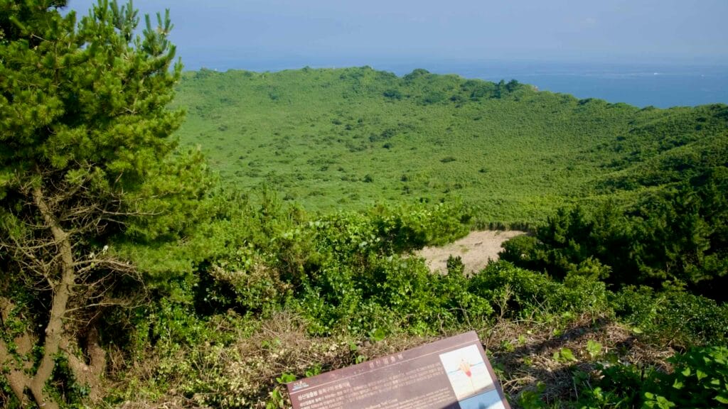 An interpretive sign stands at the rim of Seongsan Ilchulbong, overlooking the bowl-shaped crater.