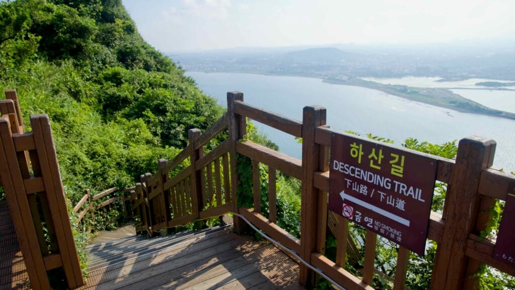 A “Descending Trail” sign marks the stairway on Seongsan Ilchulbong, where wooden railings.
