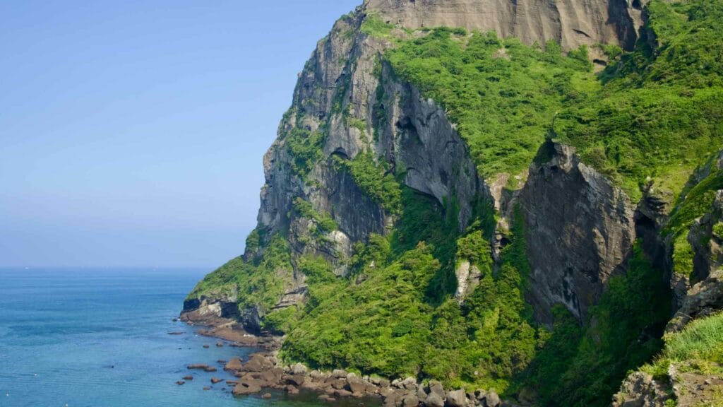 A crescent of black sand nestles below Seongsan Ilchulbong on Jeju’s scenic Umutgae Coast.
