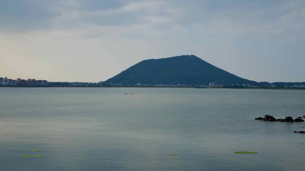 Jimibong Peak rises beyond the tranquil blue waters of the Ojo-ri lagoon.