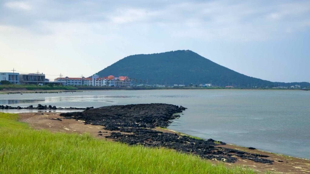 Basalt flats stretch toward Jimibong Peak as guesthouses line the quiet bay at Songnan Port.