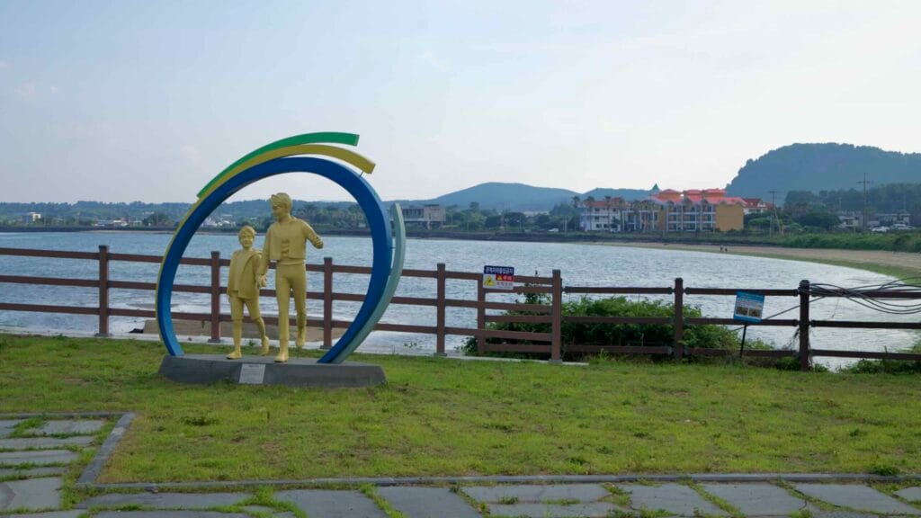 A ring-framed family statue stands beside the waterfront lawn at Songnan Port.