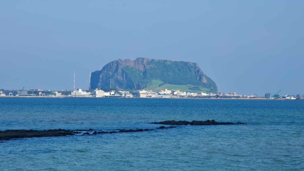 Seongsan Ilchulbong rises above the waterfront across the calm waters of Songnan Port.