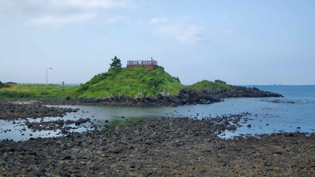 A timber viewing deck crowns a low lava islet just outside Dumun Port overlooking the sea.