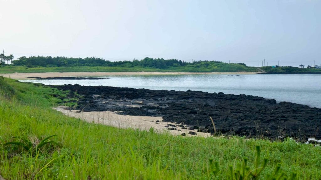 Basalt flats and sandy patches edge the tranquil turquoise water at Hado Beach.