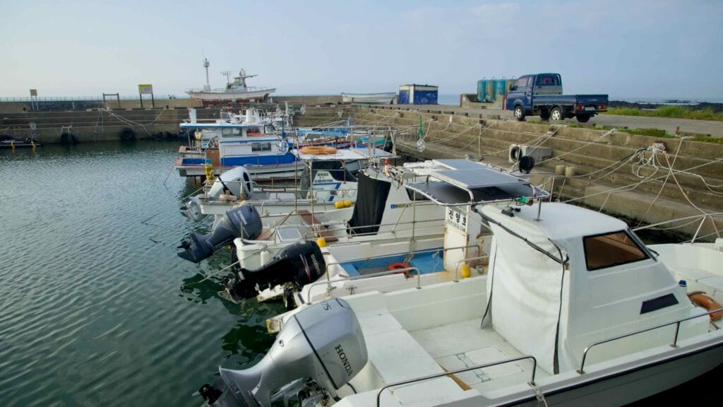 Small fishing boats with outboards are moored inside the sheltered Hado Port.