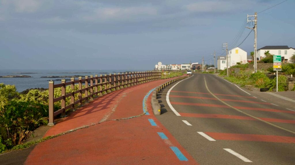 Morning light glows along the red coastal bikeway and road beside Hado’s shoreline.