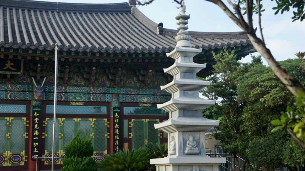 A tiered stone pagoda rises before the main hall at Yongmunsa Temple on Jeju’s east coast.