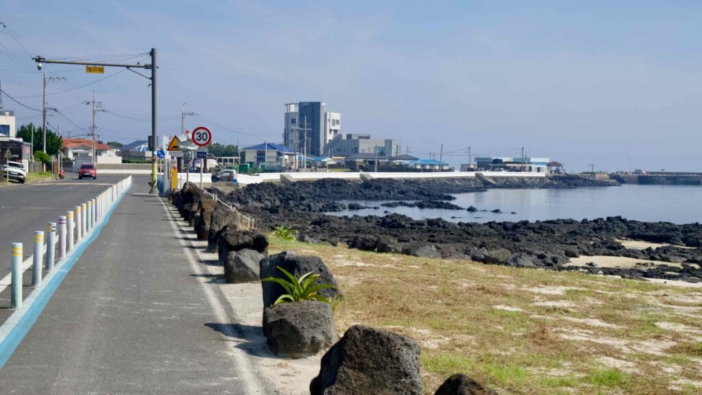 A coastal bike lane in Handong-ri runs beside the seawall above volcanic rocks.