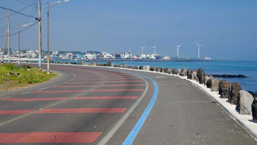 A coastal road and bike lane curve toward Woljeongri Port and Beach.