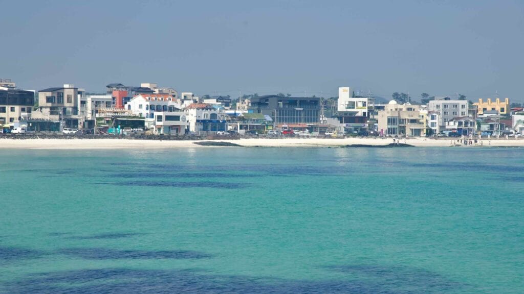 Woljeongri’s cafe‑lined waterfront sits behind white sand and clear water.