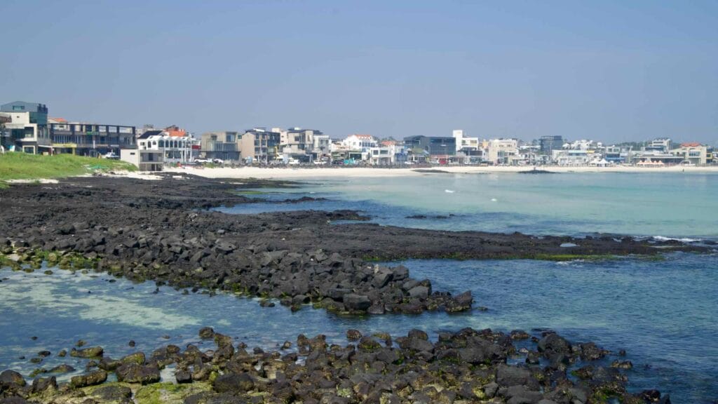 Emerald shallows and basalt boulders lead toward Woljeongri’s beaches.