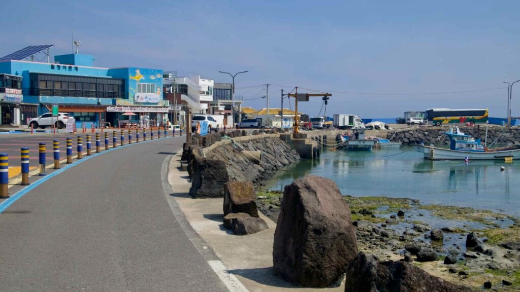 A curving harbor road passes small boats at Woljeongri Port.