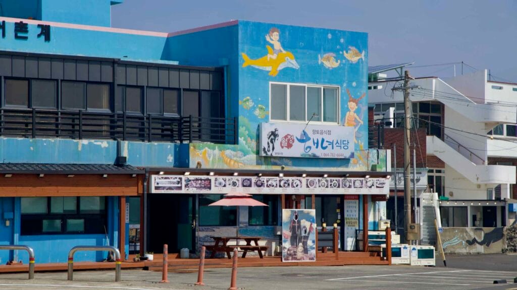A sea‑life mural decorates a haenyeo‑themed restaurant at the port.