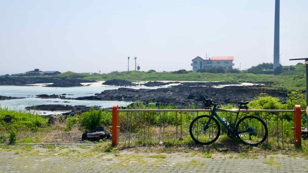 A road bike overlooks basalt lagoons and a distant turbine.
