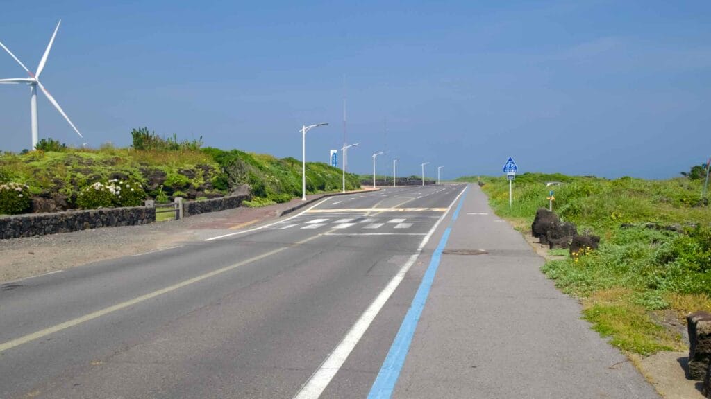 Coastal road and blue bike lane head toward Gimnyeong Seongsegi Beach.