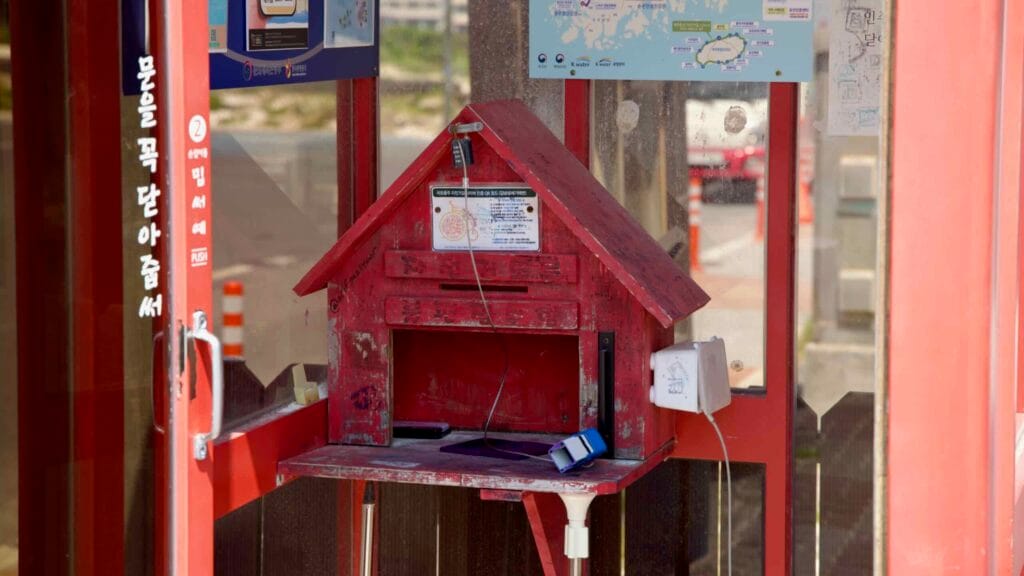 Red stamp box and route maps inside the Gimnyeong Seongsegi Beach certification booth.