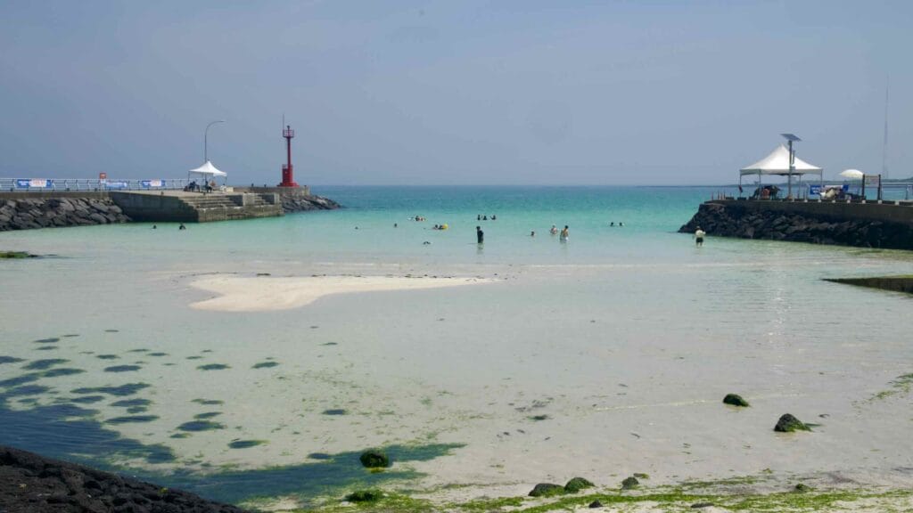 Basalt reefs front the pale sands and turquoise cove of Segial Beach at Gimnyeong.