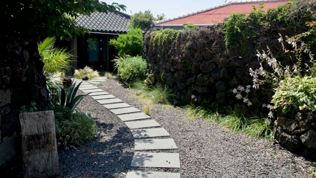 A stepping-stone garden path leads past walls to a house in Gimnyeong’s mural village.