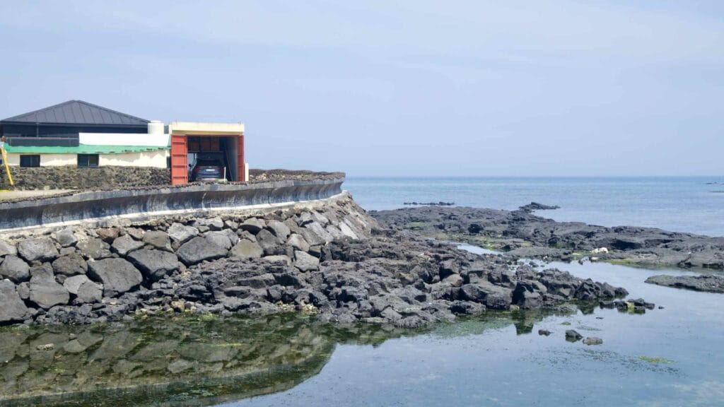 A renovated seaside house and garage sit above a curved seawall at Gimnyeong.