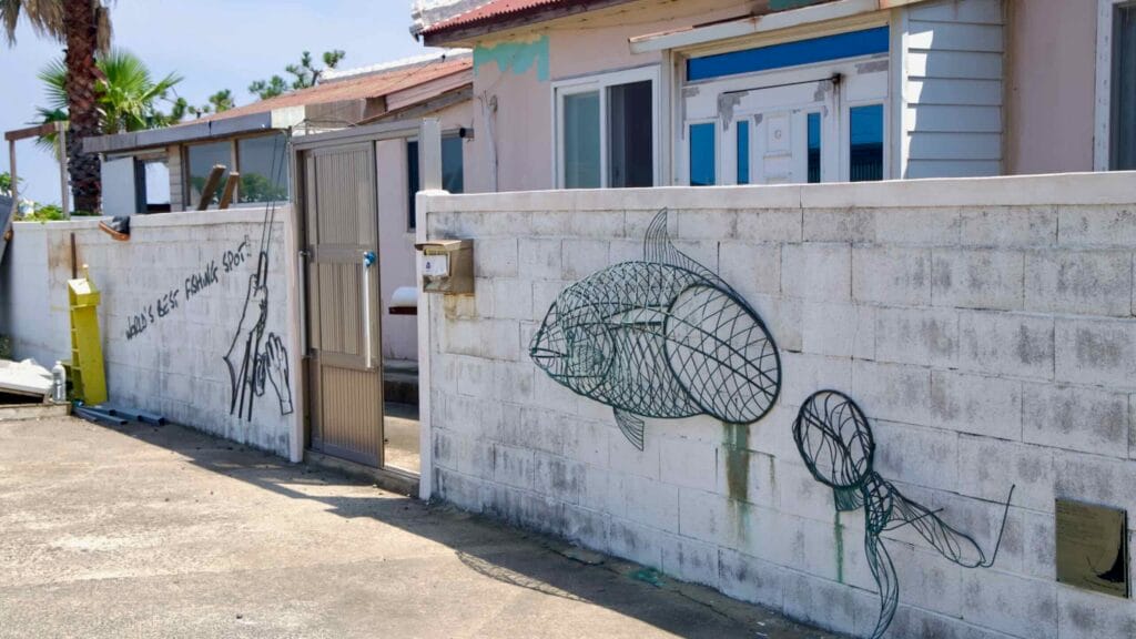 Wire-art figures of a diver and fish decorate a wall in Gimnyeong’s mural village.