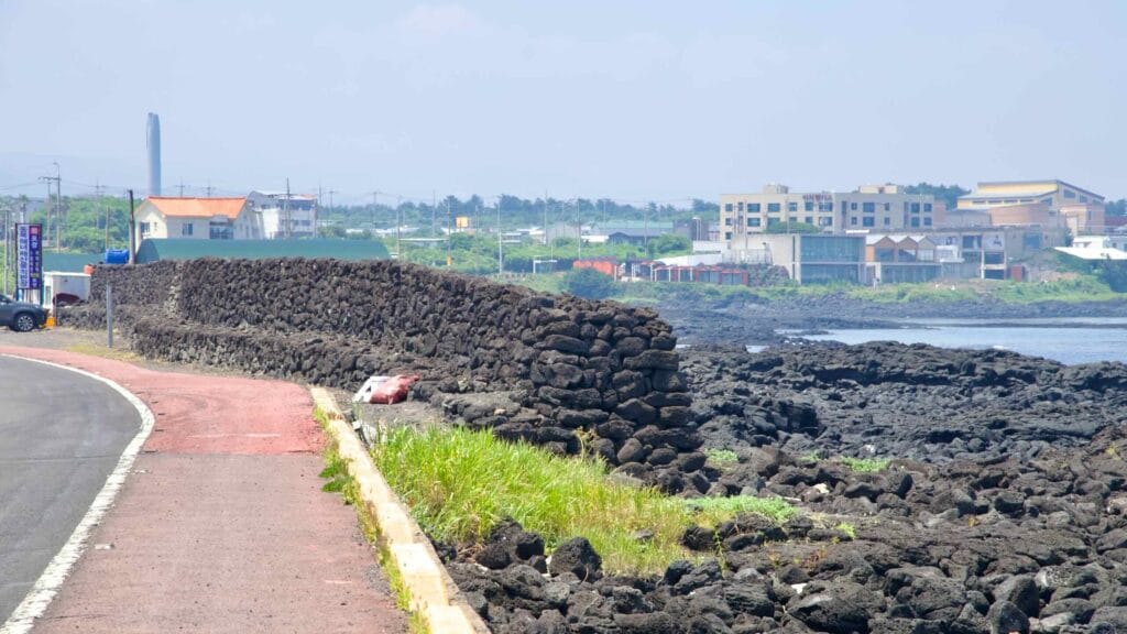 A basalt seawall lines the Dongbok shoreline beside the road and bike path.