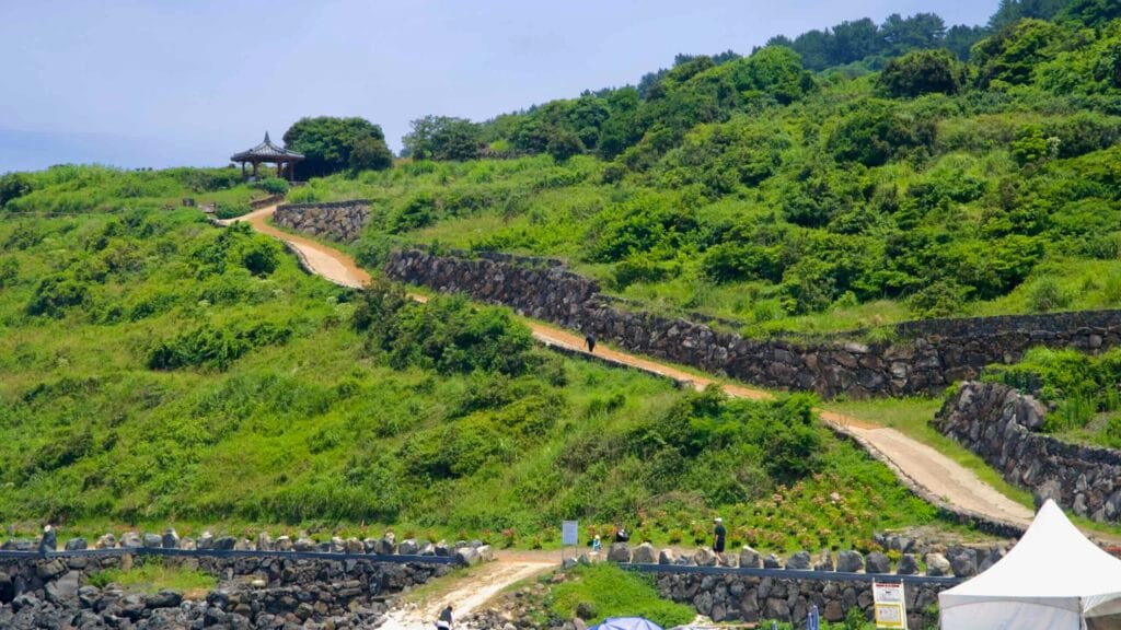 A stepped trail and stone walls climb Seoubong above Hamdeok Beach.