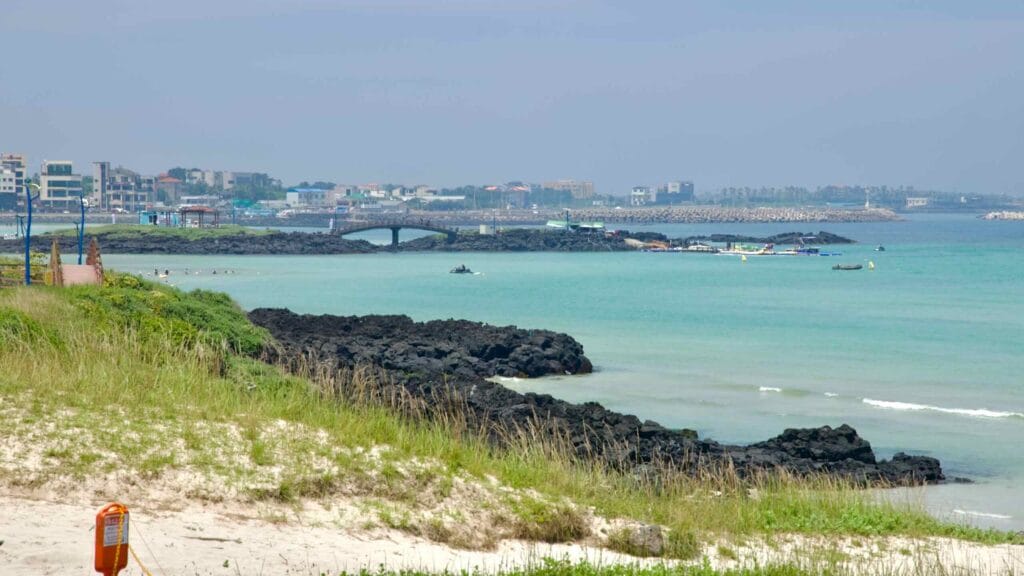 The view from Hamdeok spans lava headlands toward a pedestrian bridge and marina.