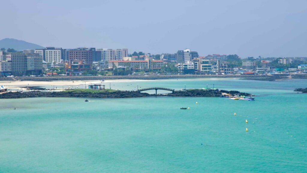 A small pedestrian bridge spans lava islets between Hamdeok’s coves.