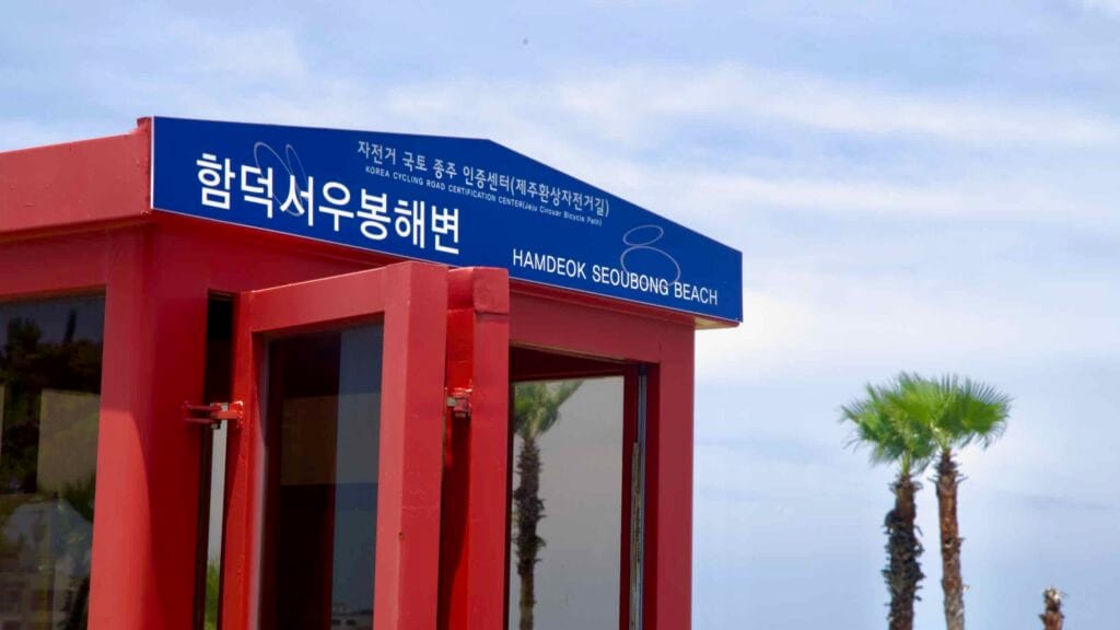 Hamdeok Seoubong Beach certification booth with palms behind.