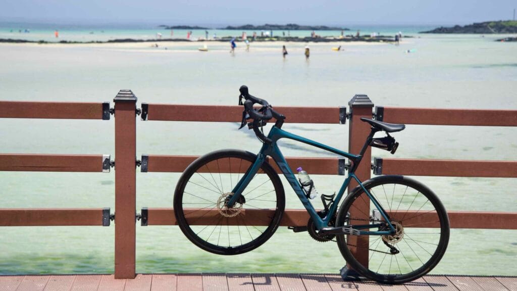 A road bike rests against the boardwalk rail at Hamdeok Seoubong Beach.