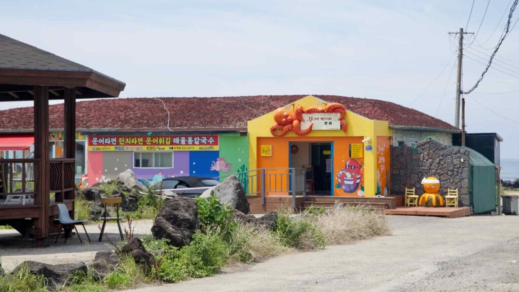 A seaside restaurant with an octopus mascot advertises seafood near Shinheung.