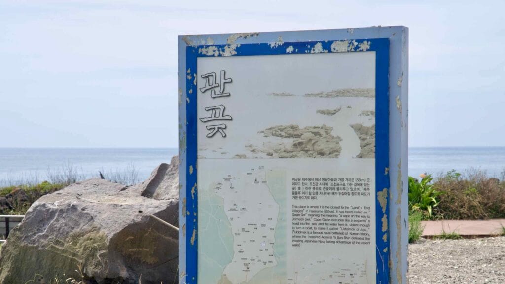 An interpretive sign titled “Pangot” stands above the rocky shore near Shinheung.