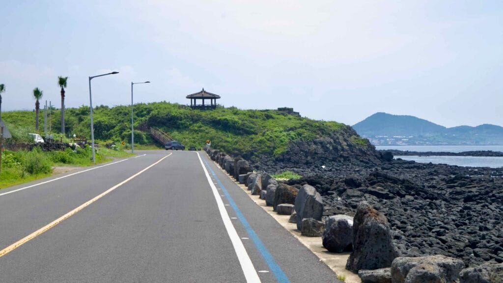 Coastal road run beneath a pavilion along a lava shoreline outside Shinheung.