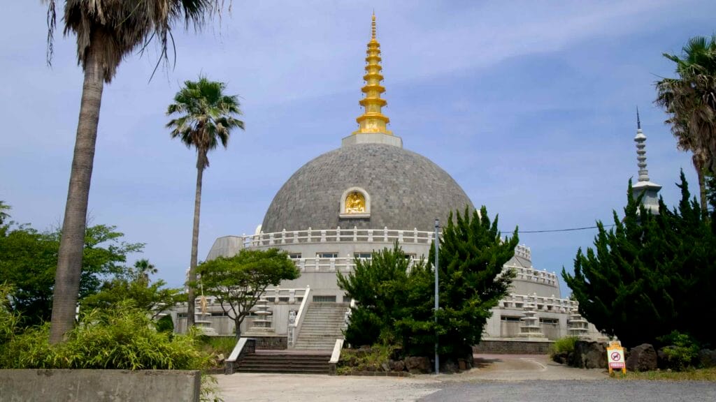 Palms and evergreens frame the Buddha Sharira Stupa, a domed monument with gilded spire.