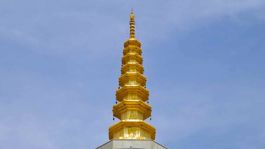 Close view shows the stupa’s gilded finial with bells and reliefs on stepped octagonal tiers.