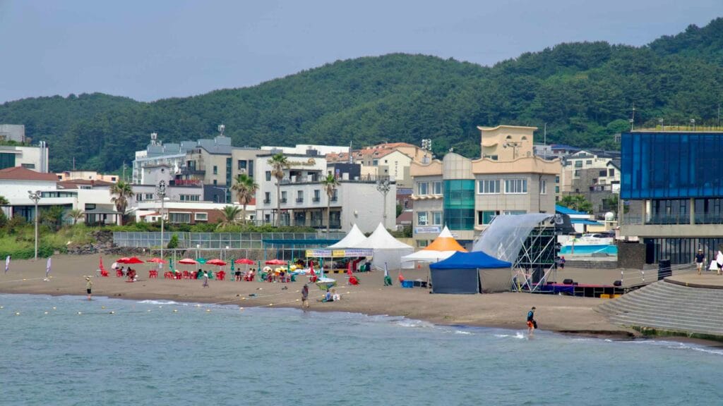 Umbrellas, tents, and a temporary stage gather by the mosaic seawall.