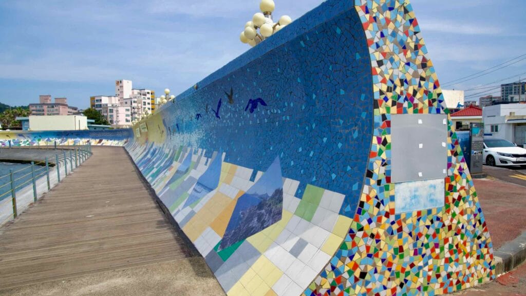 A close view shows tiled patterns on the seawall above the boardwalk.