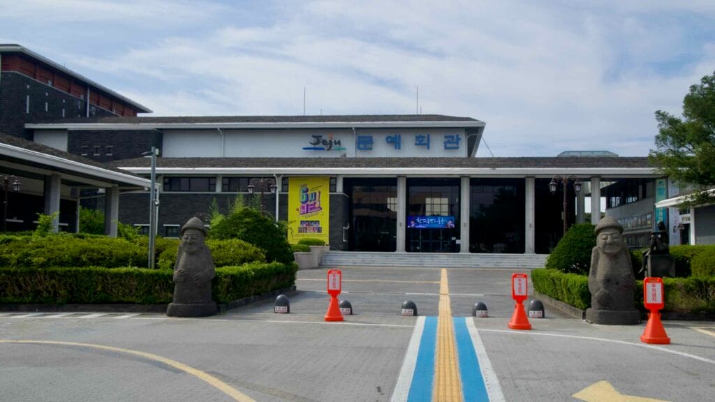 The Jeju Provincial Arts Center faces a forecourt flanked by dol hareubang statues.