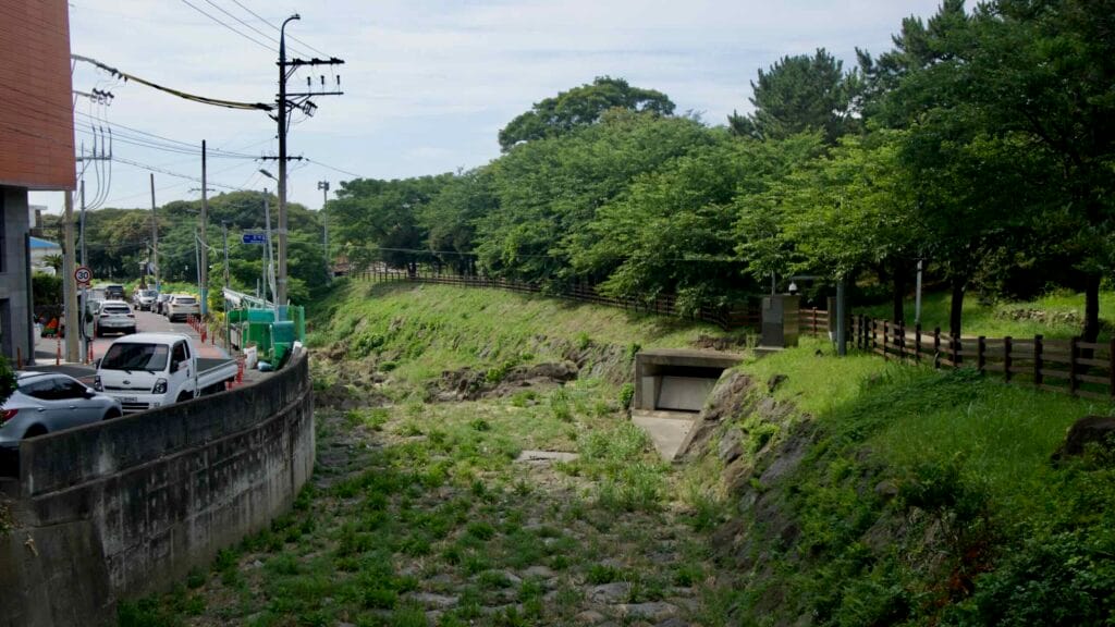 The rocky bed of Sinsan Stream lies dry beneath a park embankment.