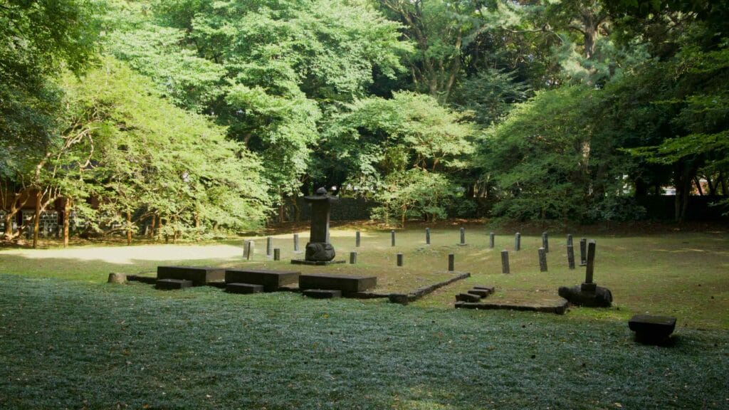 Within the inner yard, a basalt stele on a turtle pedestal stands beside a ring of short marker posts.