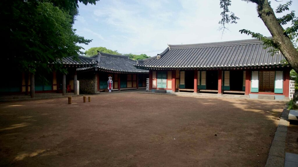 Traditional buildings enclose the Samseongjeon courtyard with an illustrated face-cutout board.