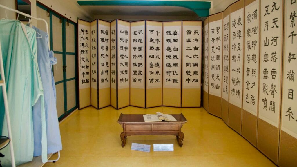 An exhibition room displays a folding calligraphy screen around a low table.