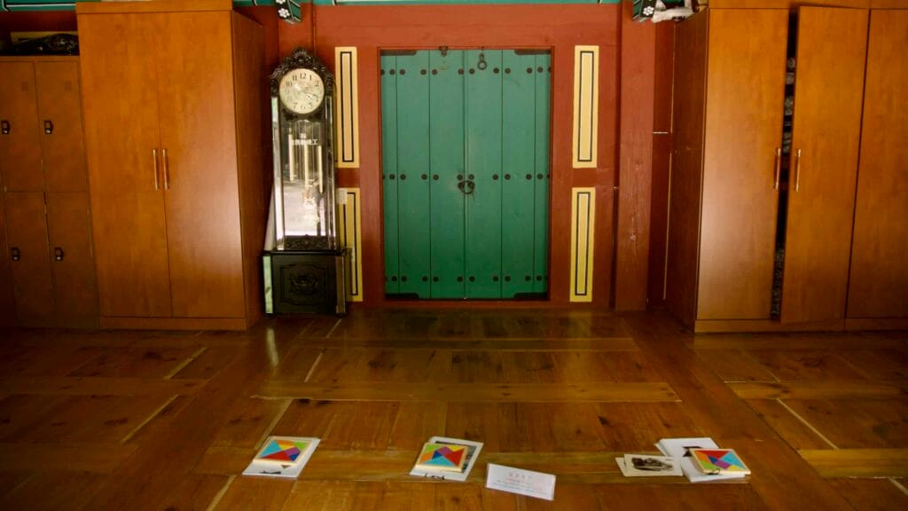 A traditional hall shows a teal wooden door flanked by wardrobes and a pendulum clock.